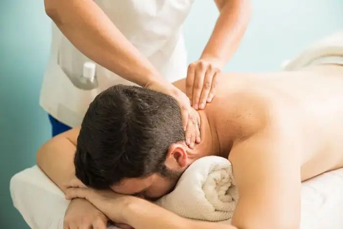 Therapist using both hands to massage a client's upper back and neck